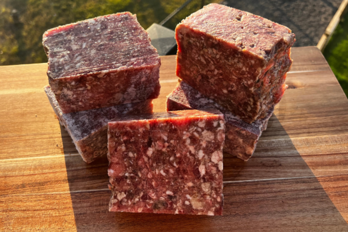4 Protein Variety Box featuring raw meat blocks on a wooden surface, highlighting premium ingredients delivered to your door.