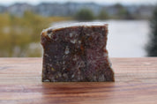 Block of beef and bison vegetable mix on wooden surface with blurred background, perfect for raw pet food.