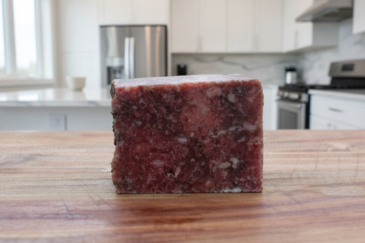 Raw chicken, beef, and bison mix for pets on a wooden surface with a blurred lake background.