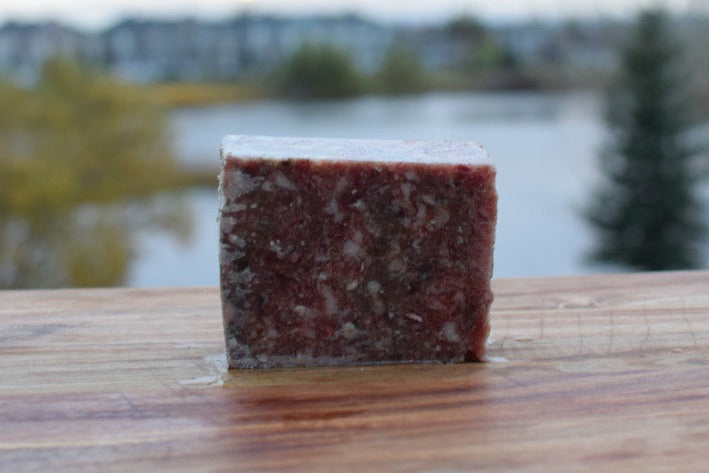 Sardine and chicken mix block on wooden surface, showcasing human-grade raw pet food made with quality ingredients.
